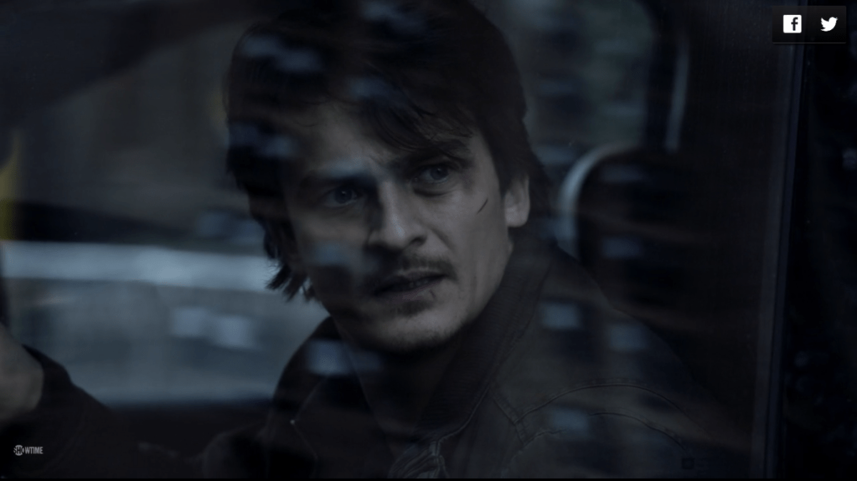 A bruised Quinn looks out the window of a car from the driver's seat.