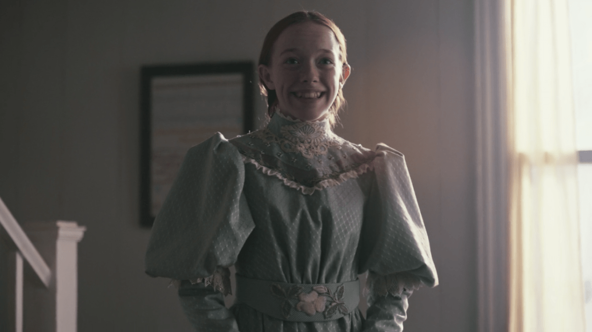 Anne wears a dress with leg-o-mutton sleeves and smiles.