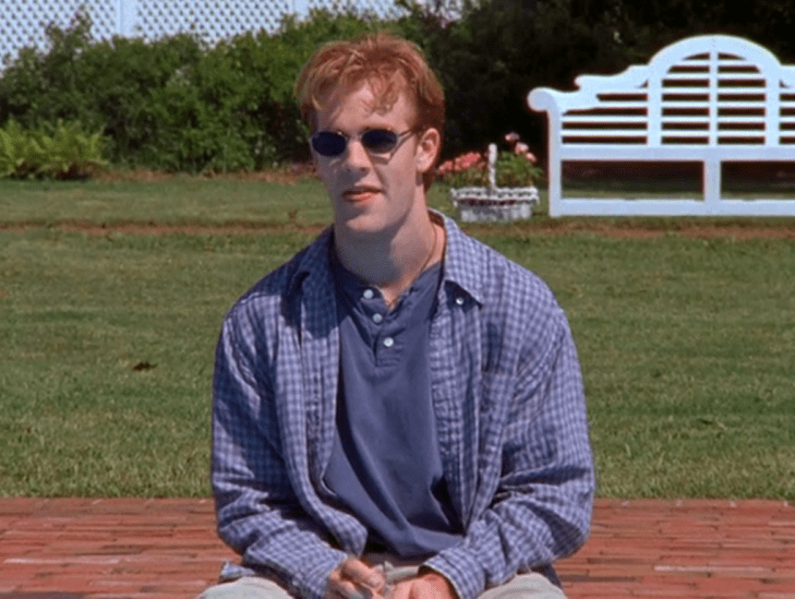 Dawson sits by a pool wearing sunglasses.