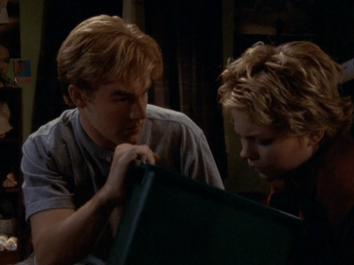 Dawson holds up a wastebasket while Jen leans over it looking sick.