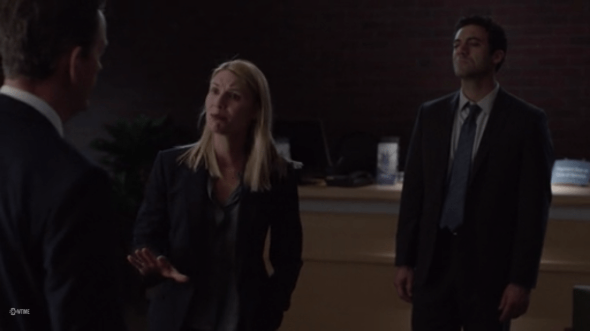 Carrie makes an urgent pleading face as she talks to a man whose face is not visible (Paley) while standing between him and New Quinn.