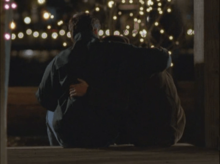 Joey and Jack sitting facing away from the camera with arms around each other, twinkle lights all around.