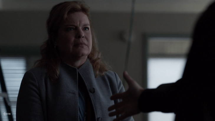 Sandy stares with a wrinkled forehead as a man (offscreen) extends his hand towards her.