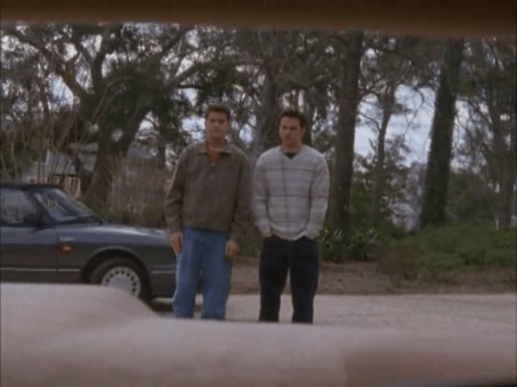 Pacey and Jack are visible through the back window of a car, awkwardly holding their hands by their sides.