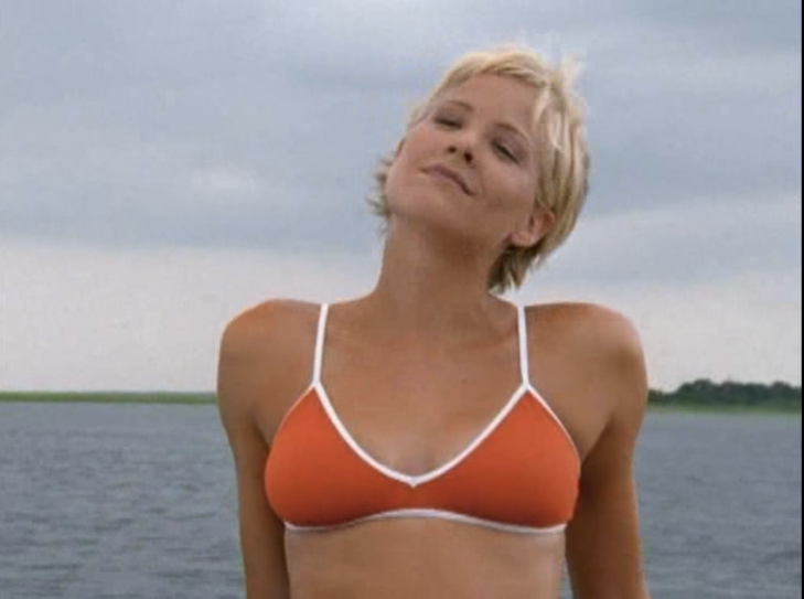 Eve leans back, open water behind her, wearing a red bikini top with white piping.