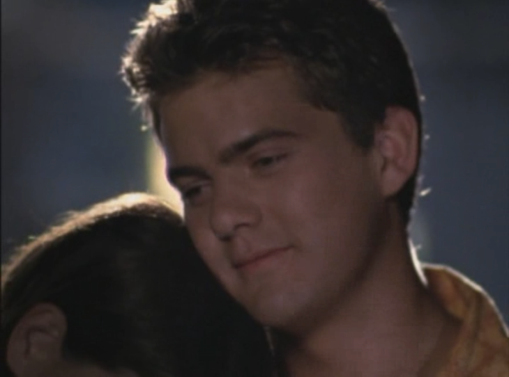 Closeup of Pacey resting his chin on the top of Joey's head and smiling.