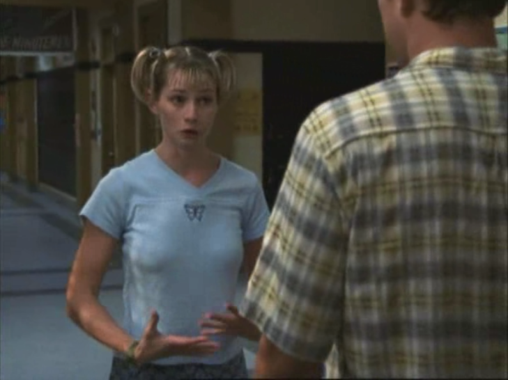 Andie, looking nervous, talking to Pacey (facing away from the camera). Her hair is in two extremely perky pigtails on top of her head.