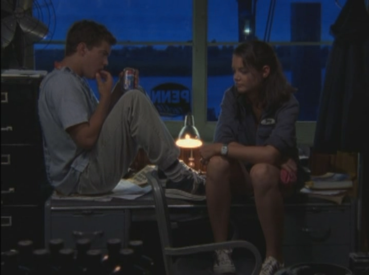 Pacey and Joey sitting on a desk in the moonlight. Pacey is touching his lip and holding a can of soda, Joey resting her elbows on her knees.