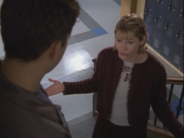 Shot of Andie standing on the stairs (back of Pacey's head in the foreground) wearing a wine sweater, another sweater, and a wine sweater skirt.