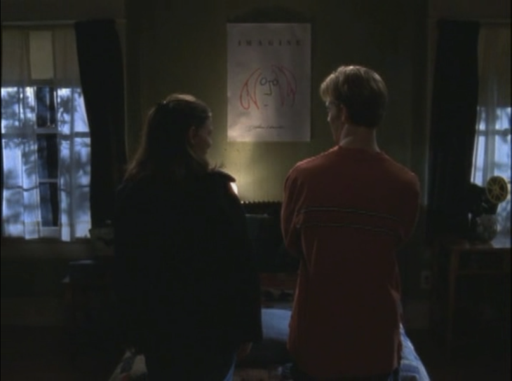 Joey and Dawson are seen from the back as they stand in front of an IMAGINE poster on Dawson's bedroom wall.