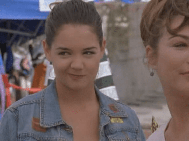 Joey, wearing a jean jacket, smiles to herself and looks to her right.