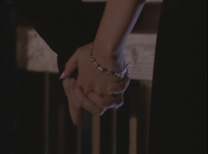 Joey's hand (holding Jack's hand), with a bracelet that is sort of like these silver metal balls joined by silver metal tubes.