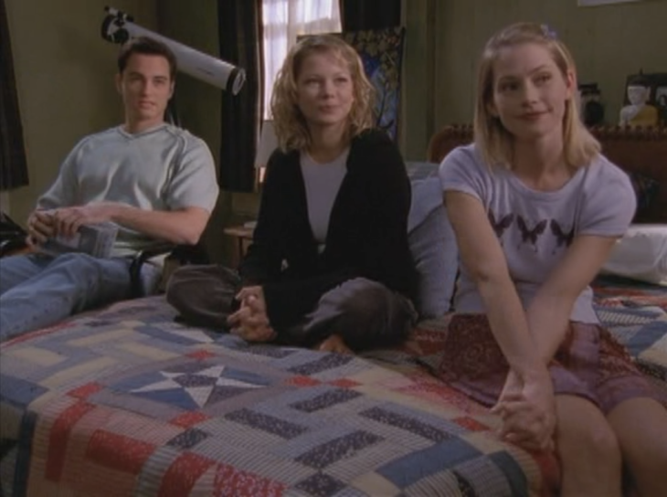 Jen, Andie, and Jack sit in Dawson's room, Jack holding videos on a chair, Jen and Andie on the bed.