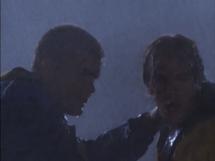 Closeup of Pacey and Dawson making intense faces in the storm. Pacey is holding Dawson's shoulder.