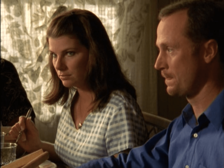 Interior kitchen table: Woman who looks just like Sandra Bullock looks up uncomfortably, holding fork