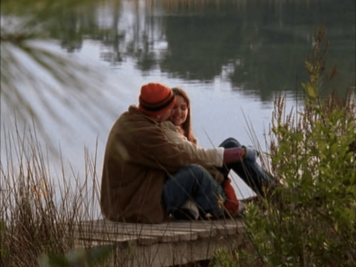 Exterior, day. Wearing winter clothes, Pacey and Joey cuddle on the dock in front of the water.