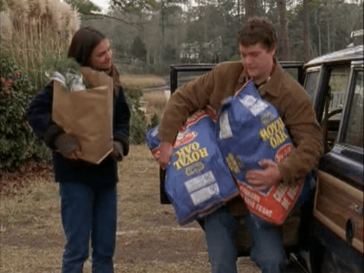 Pacey tries to hold up two giant bags of coal while Joey carries a single dainty bag of groceries.