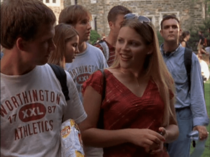 Blonde woman (Audrey) in a low-cut shirt gives a charming smile to a white guy in a Worthington Athletics t-shirt.