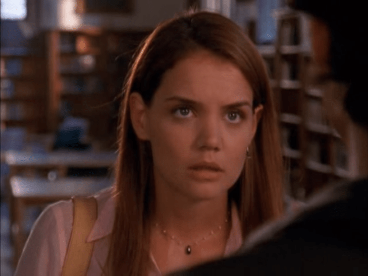 Medium shot of Joey, glaring, in a library. Shoulder of a man (professor Wilder) is seen from behind.