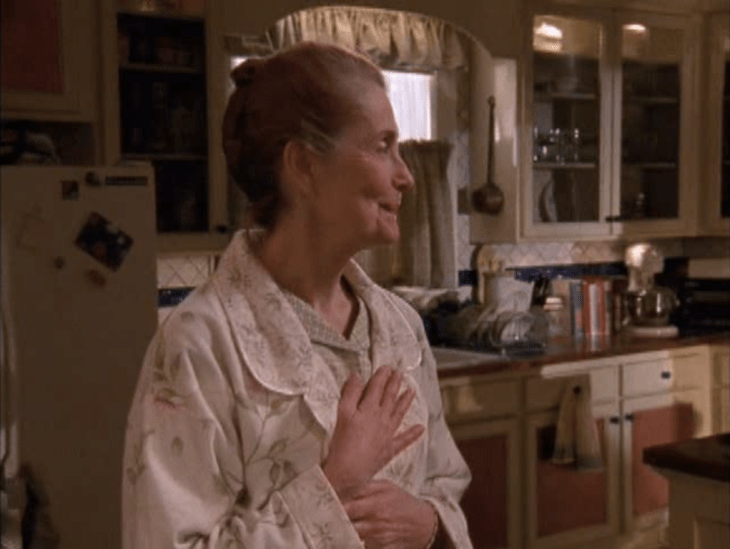 Grams looks to her right, her hands over her heart, smiling.