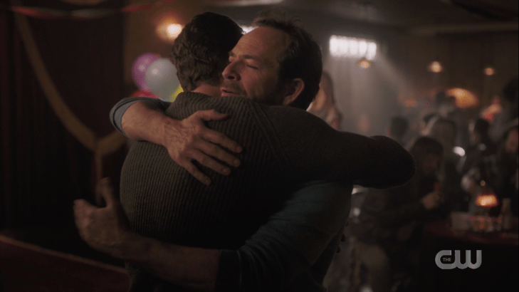 Fred hugs FP in a crowded, dimly lit bar hung with streamers.