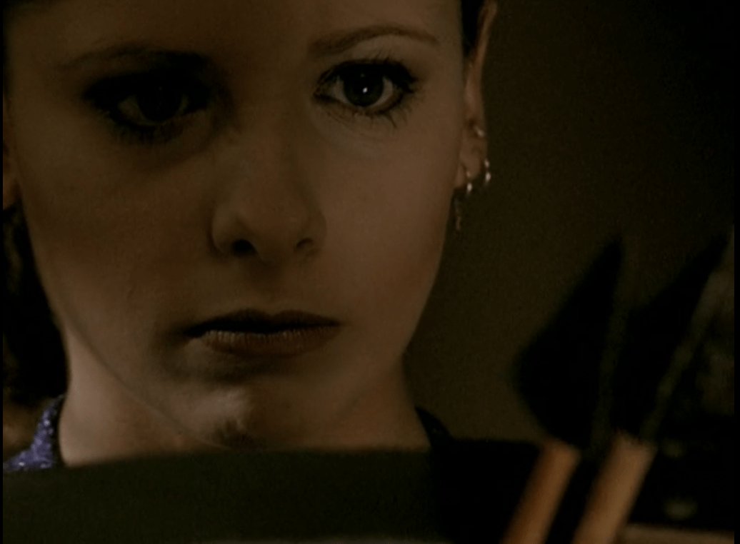 Buffy looks straight ahead with an intense expression, two arrowheads in front of her face.