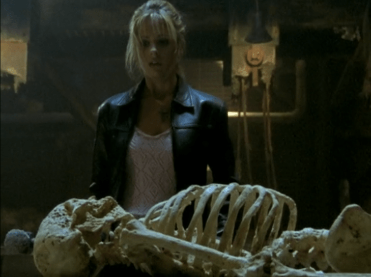 Buffy stands above a skeleton, holding a sledgehammer,