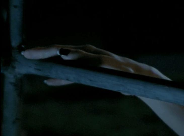 A hand holds a railing. The hand has black fingernail polish with white French tips.