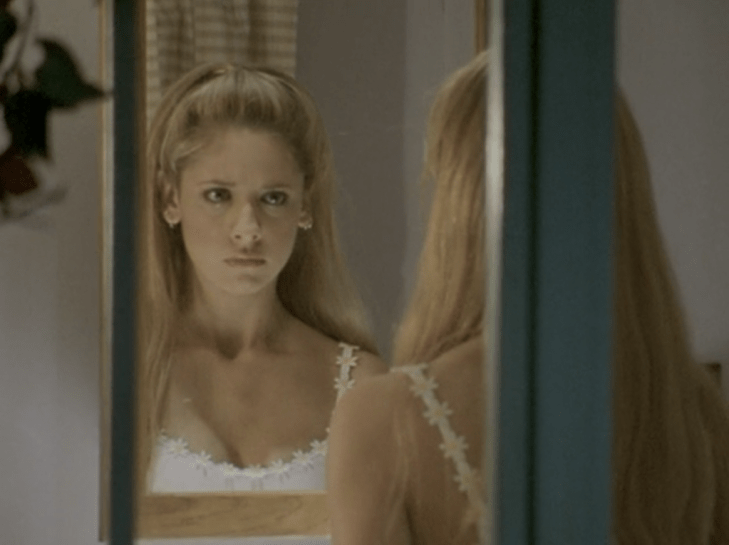 A young Buffy stares at herself in the mirror.