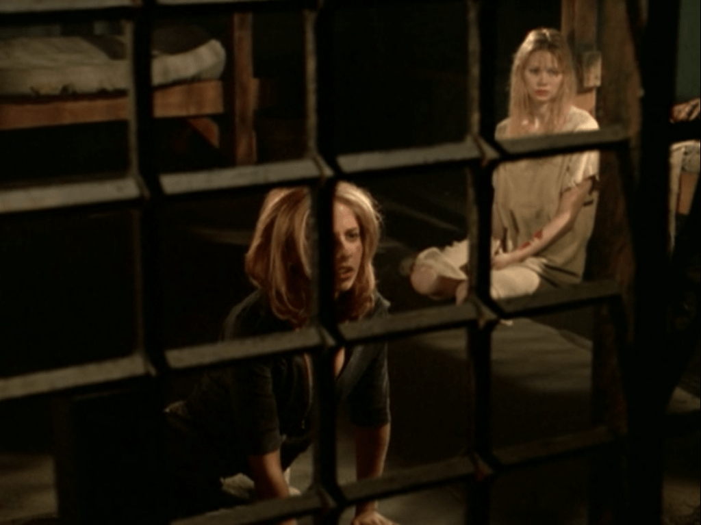 Buffy and another young woman sit in a jail cell
