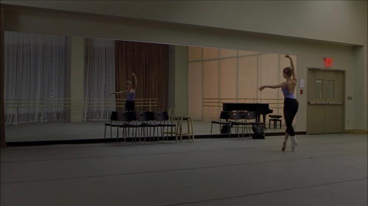 Image description: empty ballet studio where Jody stands in front of the mirror on pointe, alone.