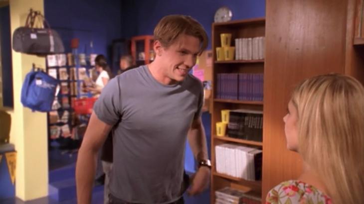 Blonde boy with side parted bangs stands in library - Riley.